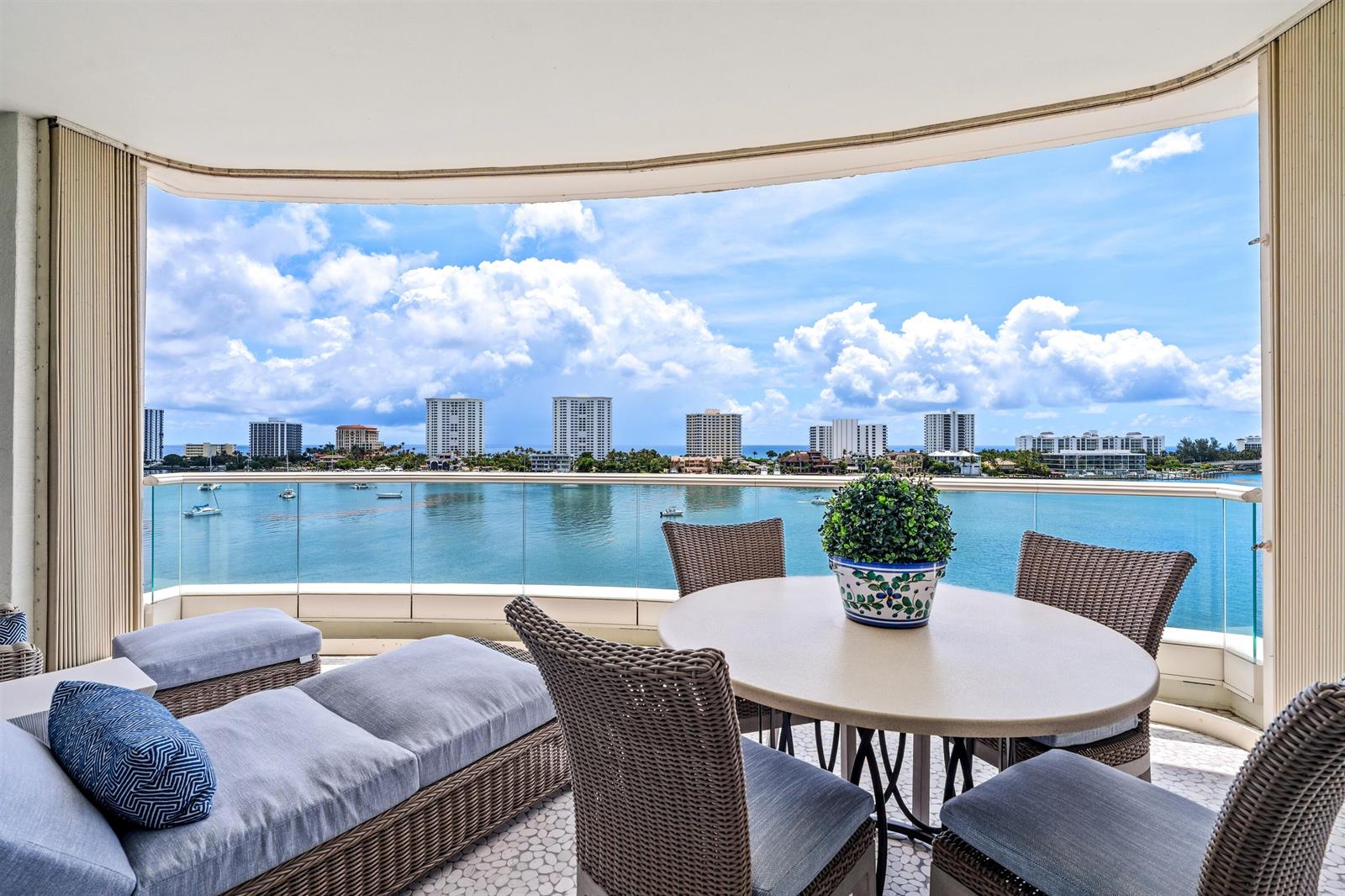 A balcony with wicker furniture and a round table overlooks a bay and city skyline — 500 SE 5th Avenue # s, Boca Raton FL 33432, BOCA RATON, FL