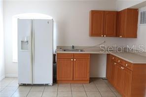 A kitchen features a white refrigerator, wood cabinets, and light-colored countertops — 2531 FAN PALM UNIT 5, DAVENPORT, FL