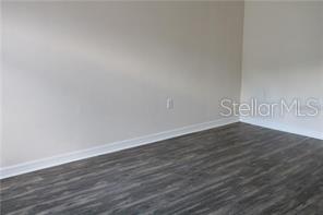 An empty room features light-colored walls, white baseboards, and dark wood-look flooring — 2531 FAN PALM UNIT 5, DAVENPORT, FL