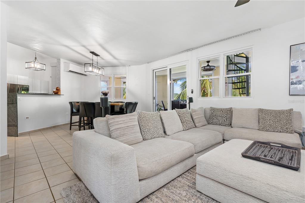 A living room with a sectional sofa, dining area, and a spiral staircase visible outside — 155 CANDELERO DRIVE UNIT D7, HUMACAO, PR