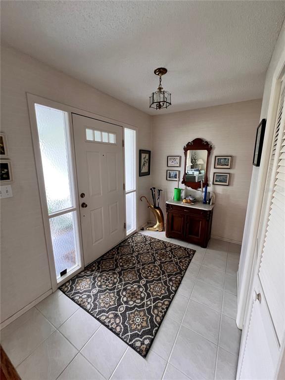 An entryway features a white front door with sidelights, a patterned rug, and a wooden console — 1530 SAN MARINO COURT, PUNTA GORDA, FL