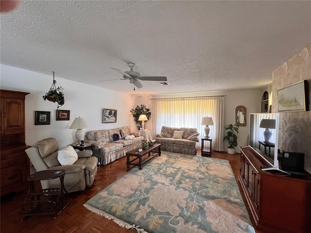 A living room features floral sofas, a patterned area rug, and wood parquet flooring — 1530 SAN MARINO COURT, PUNTA GORDA, FL