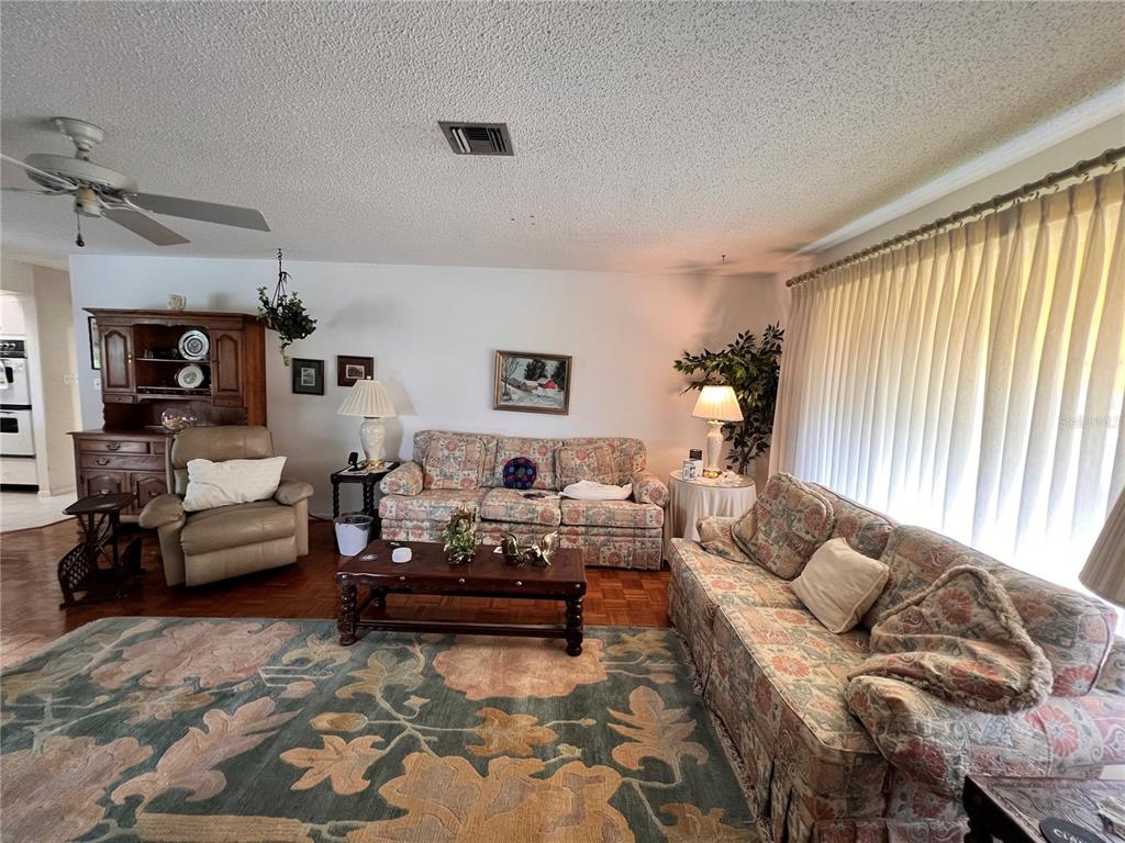 A living room features two floral sofas, a wooden hutch, and a large area rug — 1530 SAN MARINO COURT, PUNTA GORDA, FL