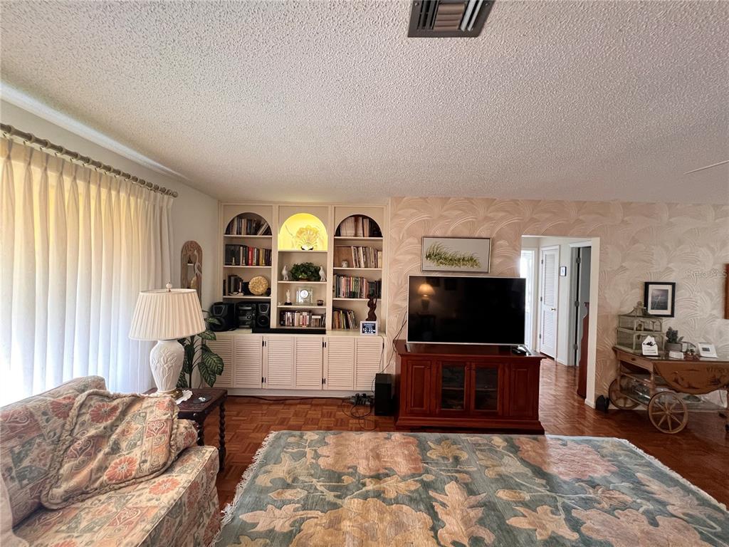 A living room features built-in shelving, a television on a wooden console, and parquet flooring — 1530 SAN MARINO COURT, PUNTA GORDA, FL