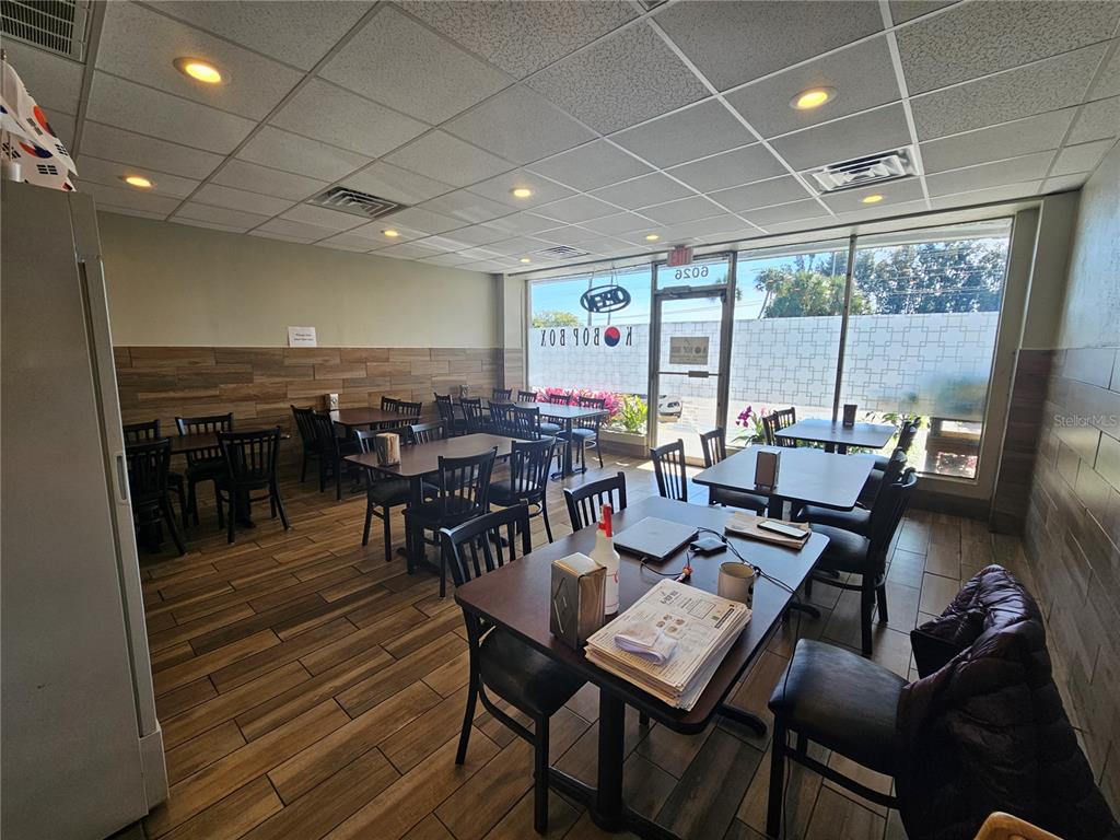 A restaurant dining area features wood-look tile flooring, tables with black chairs, and large windows — 6026 N US HWY41, APOLLO BEACH, FL