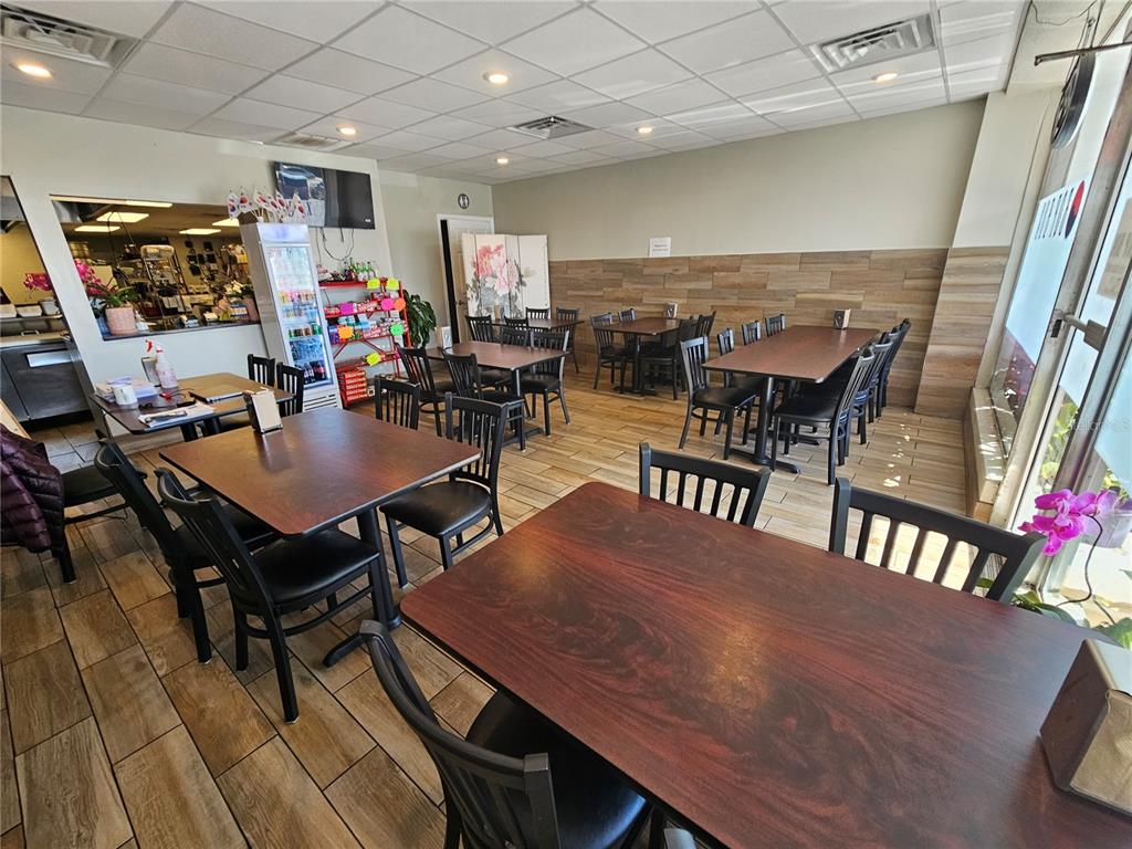 A restaurant dining room features dark wood tables, black chairs, and wood-look tile flooring — 6026 N US HWY41, APOLLO BEACH, FL