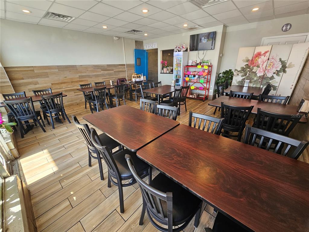 A restaurant dining room features dark wood tables, black chairs, and light wood-look tile flooring — 6026 N US HWY41, APOLLO BEACH, FL