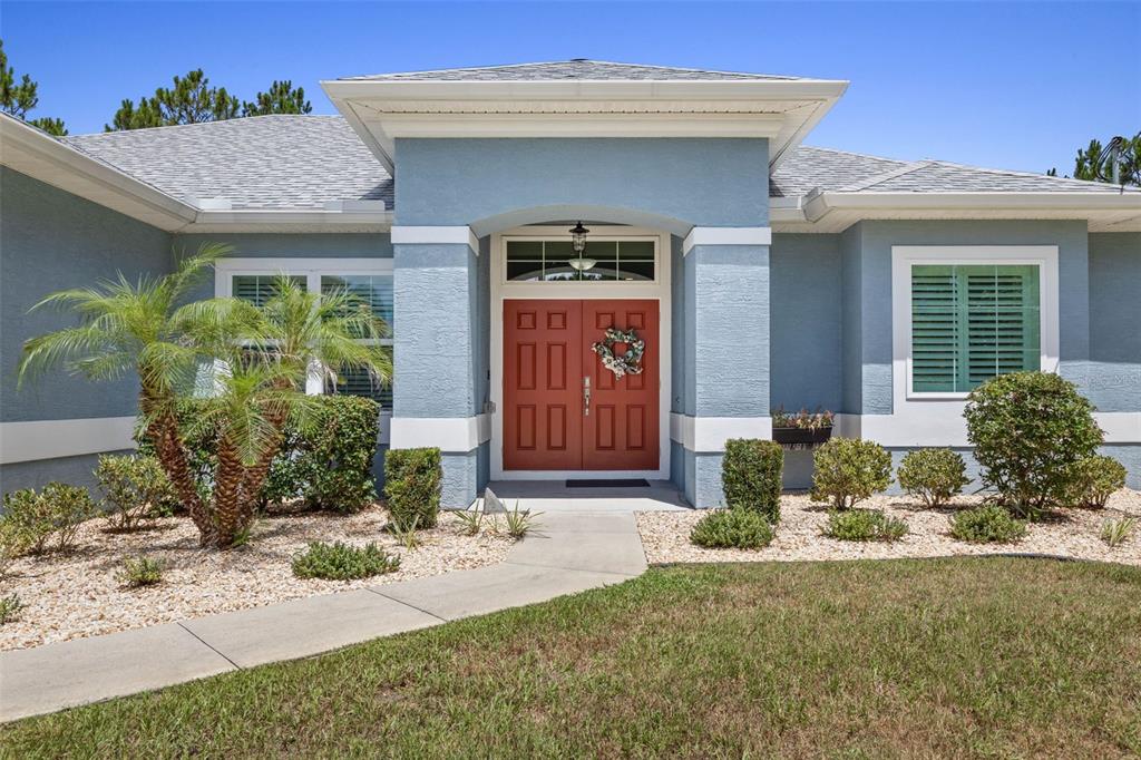 A blue house with a red double front door and a palm tree in front — 3 LEEDS PLACE, PALM COAST, FL