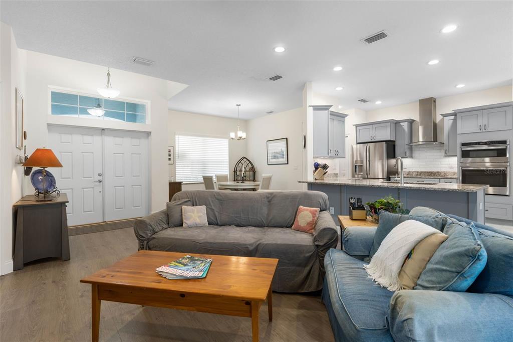 An open-concept living room features a gray sofa, a wooden coffee table, and a kitchen — 3 LEEDS PLACE, PALM COAST, FL