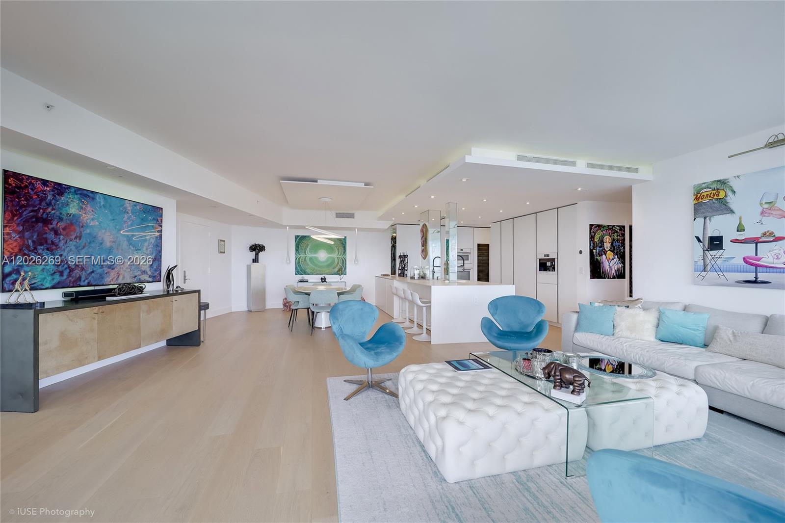 A modern open-concept living and dining area features light wood floors and contemporary art — 400 Alton Rd # 1506, Miami Beach FL 33139, MIAMI BEACH, FL