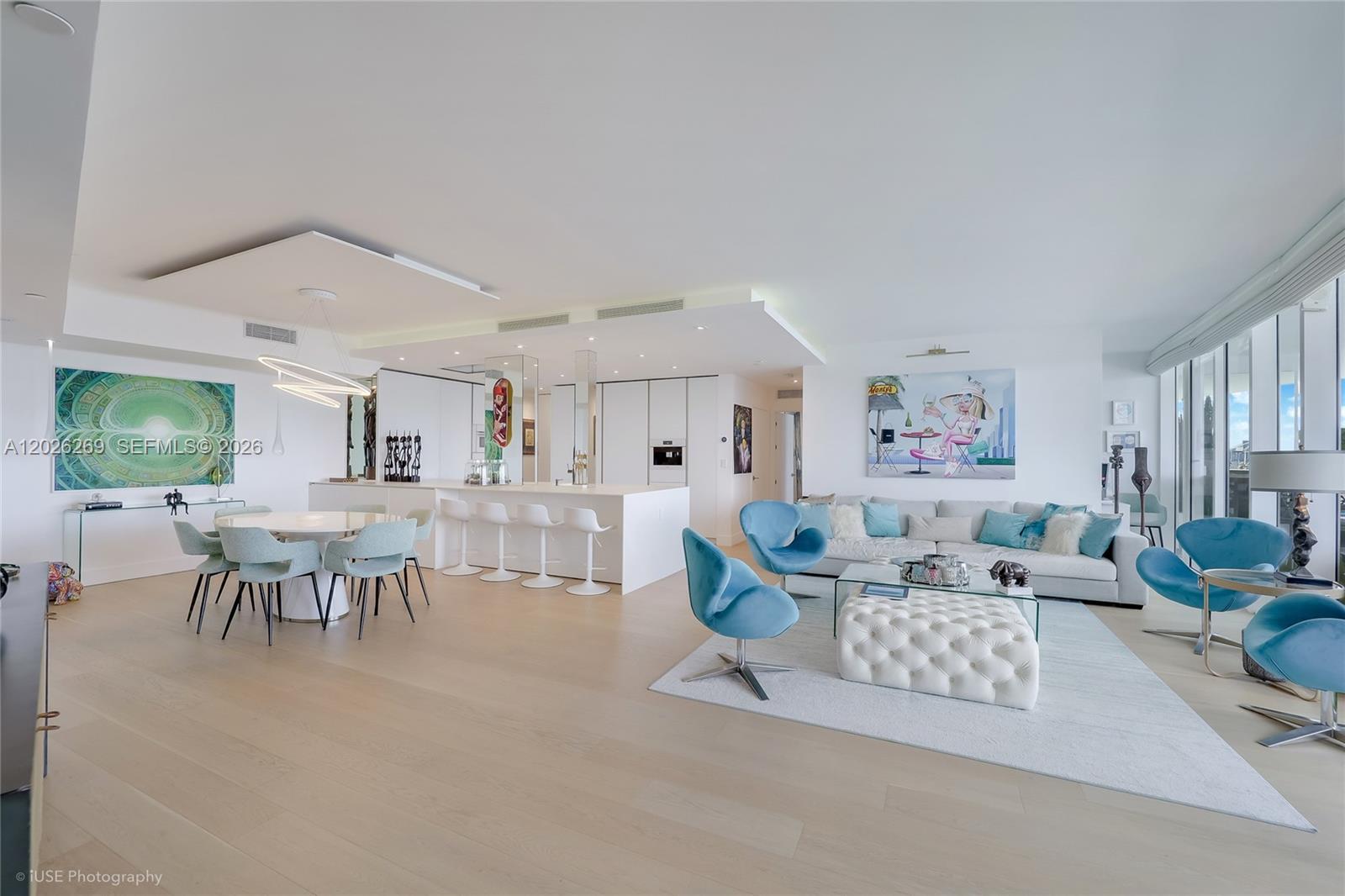 A modern, open-concept living and dining area features light wood floors and blue accent furniture — 400 Alton Rd # 1506, Miami Beach FL 33139, MIAMI BEACH, FL