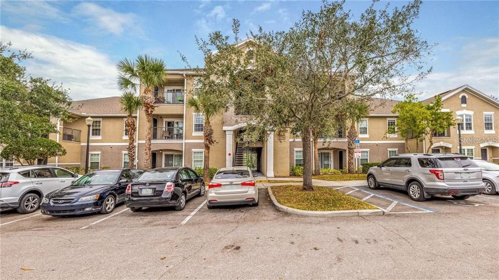 A multi-story apartment building exterior with a parking lot in the foreground — 6530 SWISSCO DRIVE UNIT 1123, ORLANDO, FL