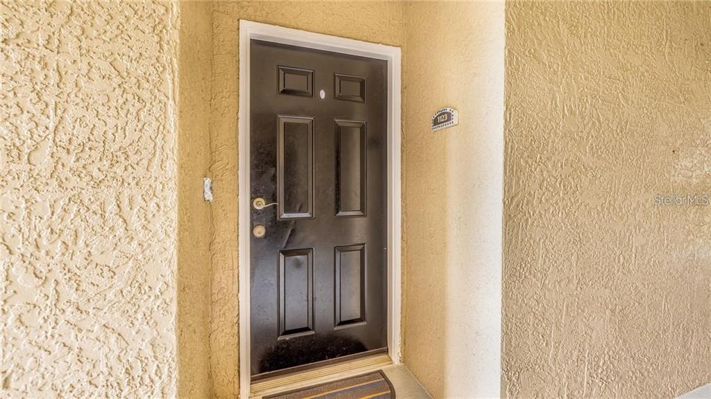 A black six-panel front door is set into a textured beige stucco exterior wall — 6530 SWISSCO DRIVE UNIT 1123, ORLANDO, FL