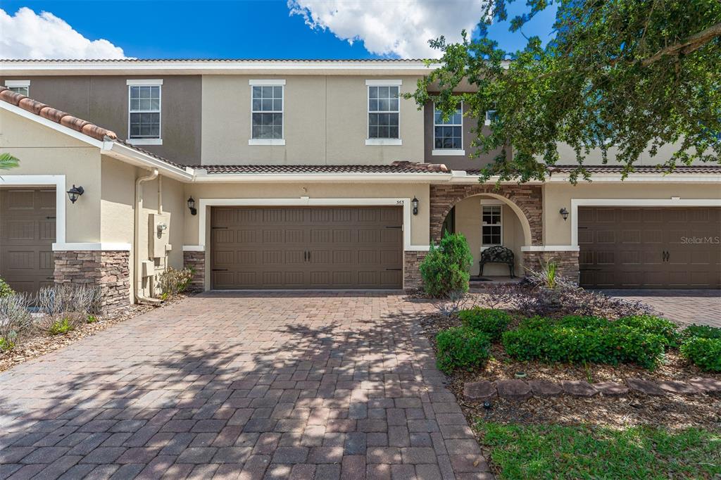 A two-story townhouse with a brown garage door, stone accents, and a paved driveway — 363 WHITE DOGWOOD LANE, OCOEE, FL