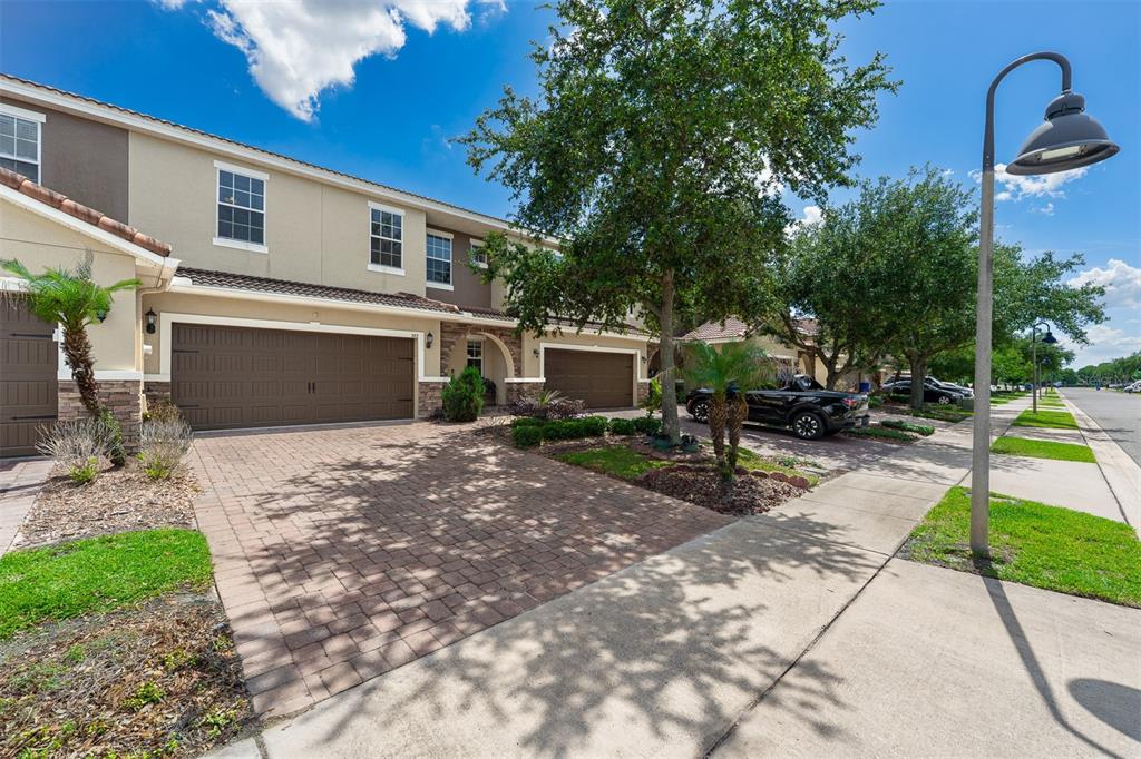 A two-story townhouse with a paved driveway, a two-car garage, and mature landscaping — 363 WHITE DOGWOOD LANE, OCOEE, FL