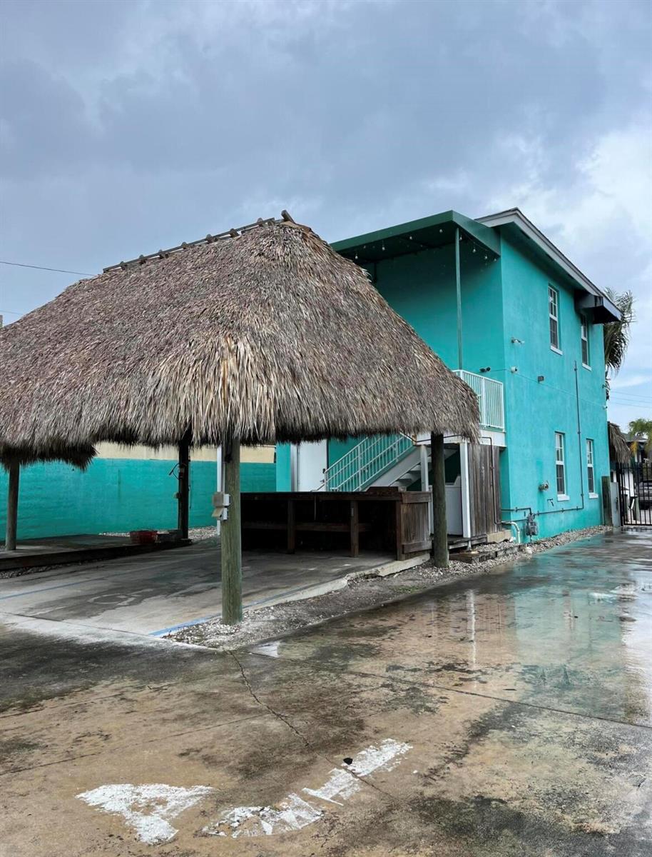 A teal two-story building features an outdoor tiki hut structure over a concrete parking area — 112 Mayfield Road, Lantana FL 33462, LANTANA, FL