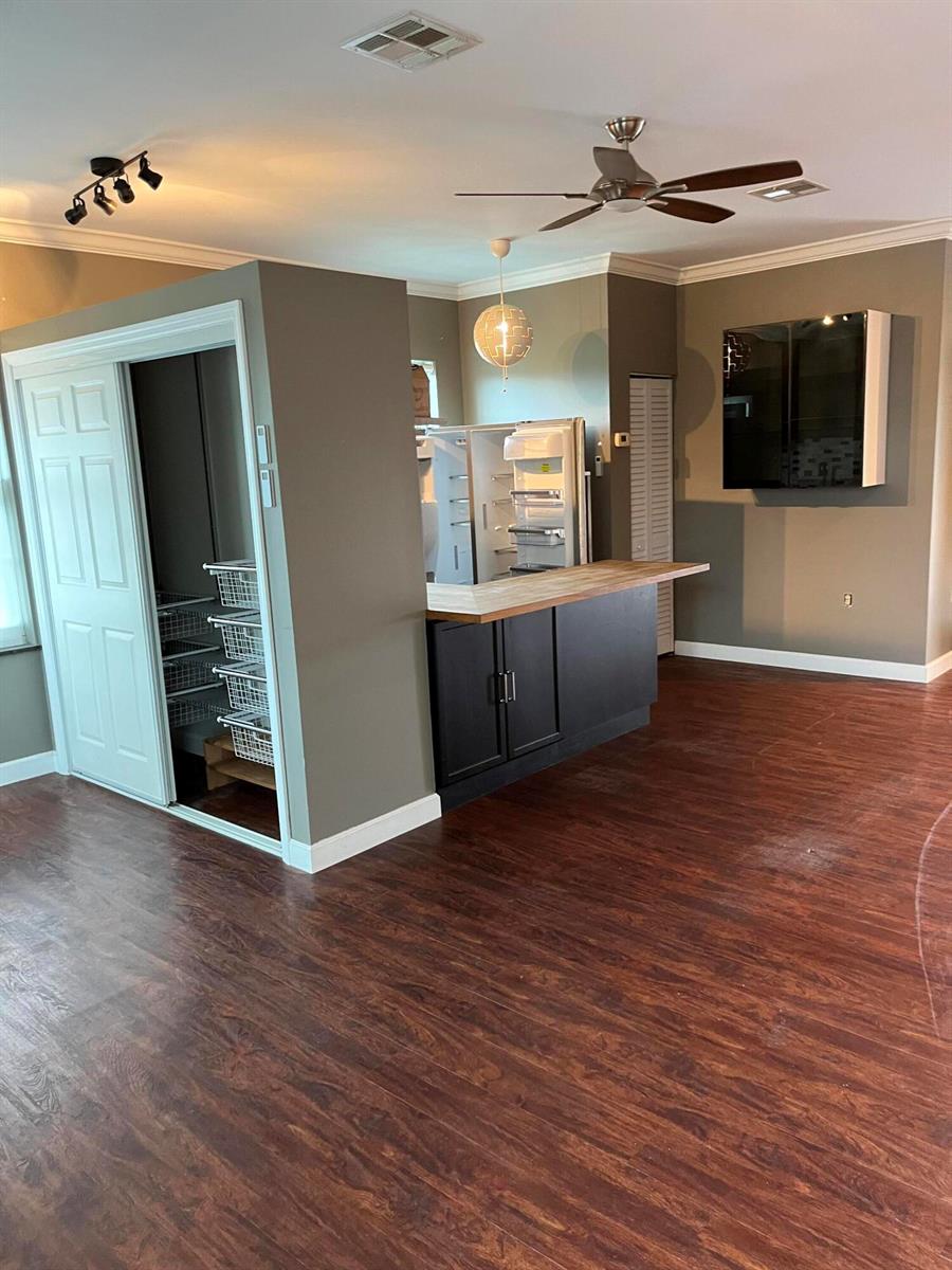 A kitchen area features dark cabinetry, a wooden countertop, a refrigerator, and a sliding-door pantry — 112 Mayfield Road, Lantana FL 33462, LANTANA, FL