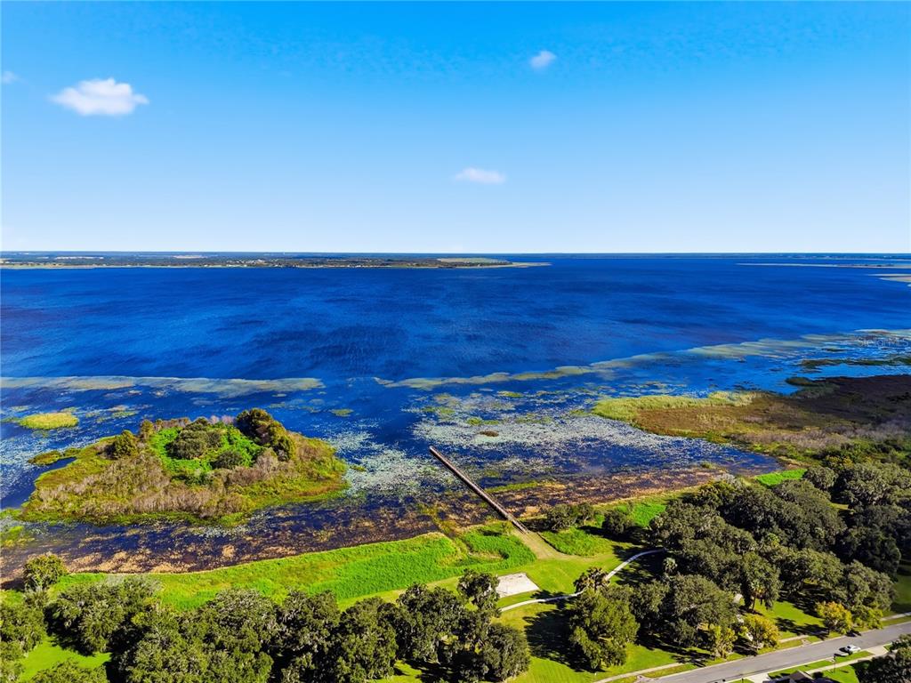 An aerial view shows a wooden dock extending into a lake near a small island — 2560 GRASMERE VIEW PARKWAY S, KISSIMMEE, FL