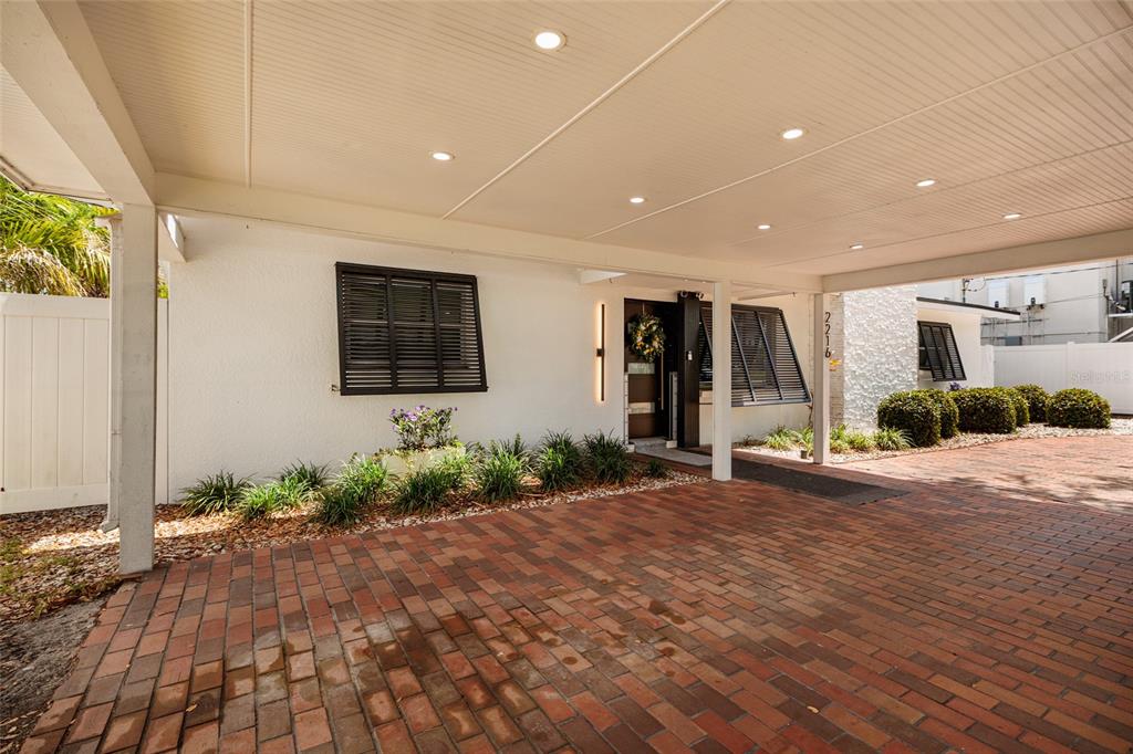 A paved driveway leads to a covered entryway with recessed lighting and a front door — 2216 S OCCIDENT STREET, TAMPA, FL
