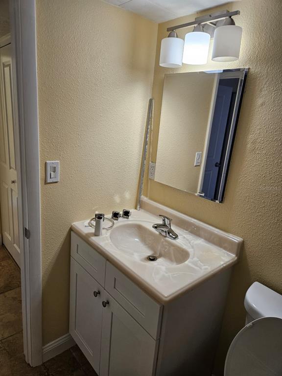 A bathroom vanity with a white cabinet, beige countertop, and a wall-mounted mirror and light — 2424 W TAMPA BAY BOULEVARD UNIT I102, TAMPA, FL