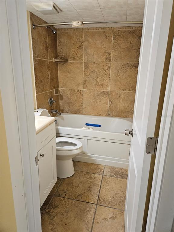 A small bathroom features a white vanity, a toilet, and a bathtub with tiled walls — 2424 W TAMPA BAY BOULEVARD UNIT I102, TAMPA, FL