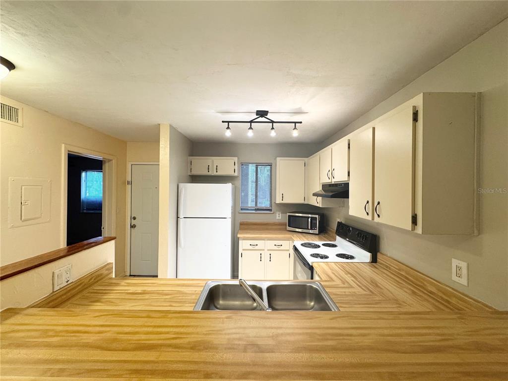 A kitchen features wood-look laminate countertops, white cabinets, a double sink, and white appliances — 109 SE 16TH AVENUE UNIT Q101, GAINESVILLE, FL