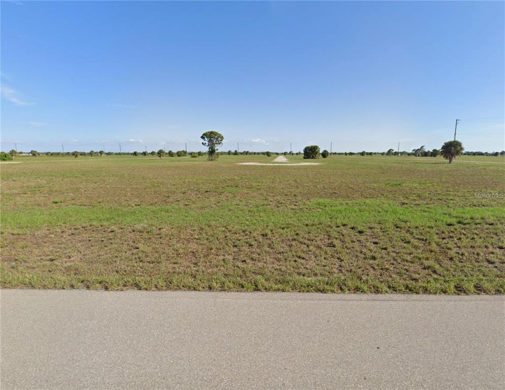 A wide, flat, grassy vacant lot viewed from an adjacent paved road — 8 ELM DRIVE, PLACIDA, FL