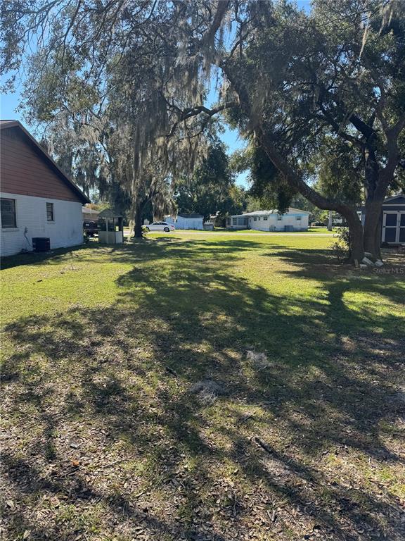 A grassy backyard area features large oak trees and a view of neighboring houses — TBD SW 97TH STREET, OCALA, FL
