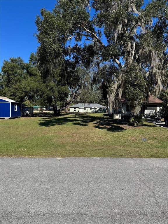 A grassy vacant lot sits between two houses under large trees with Spanish moss — TBD SW 97TH STREET, OCALA, FL