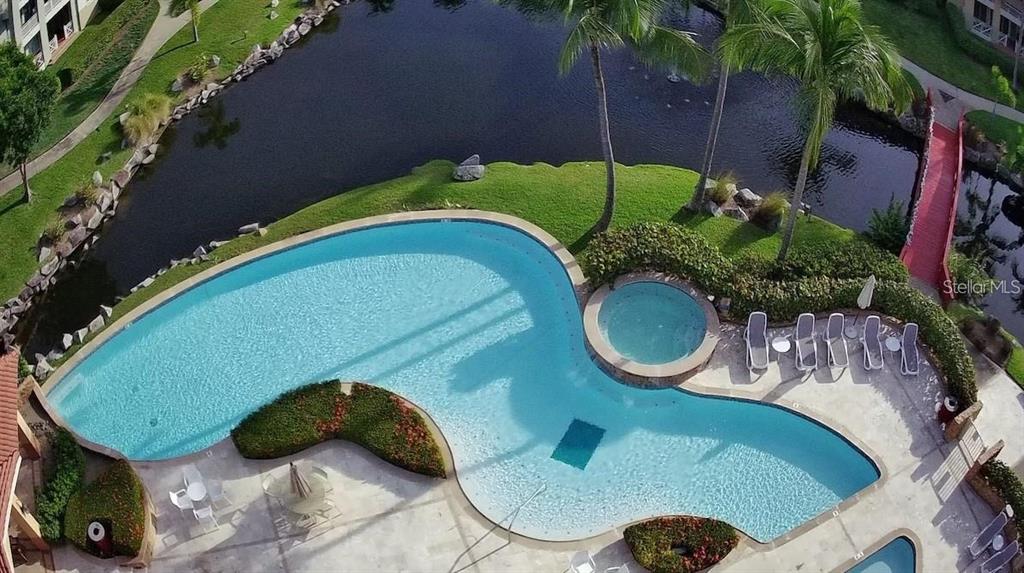 An aerial view shows a curved swimming pool and hot tub beside a pond — 75 OCEAN DRIVE UNIT 341, HUMACAO, PR