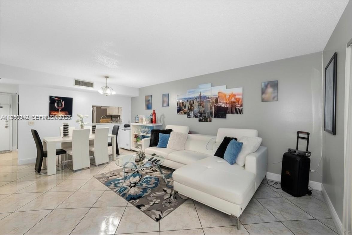 A living and dining area features white tile floors, a white sectional sofa, and artwork — 8415 SW 107th Ave # 323W, Miami FL 33173, MIAMI, FL