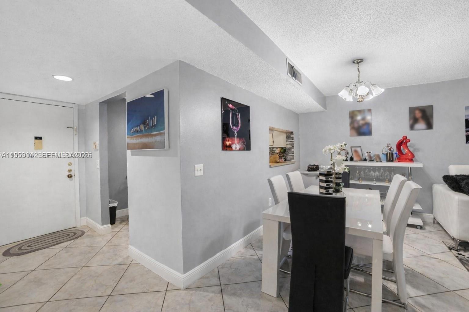 A dining area with a white table, chairs, and tile flooring next to an entryway — 8415 SW 107th Ave # 323W, Miami FL 33173, MIAMI, FL