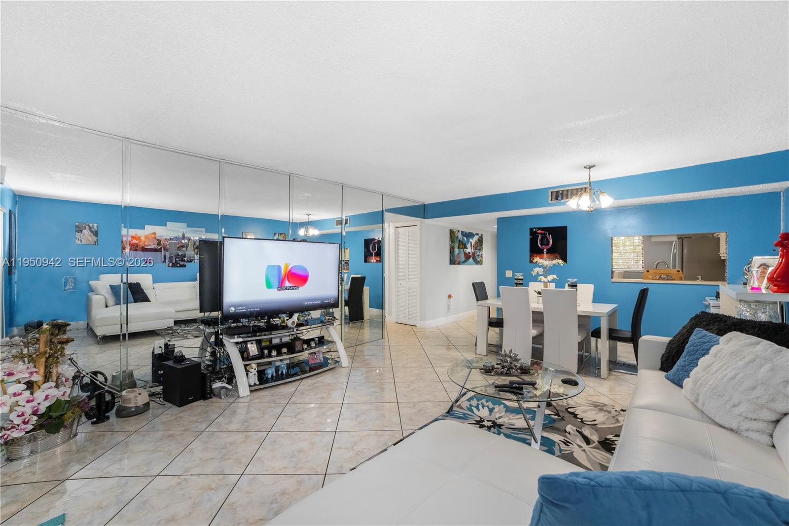 A living and dining area features blue walls, tiled floors, and a mirrored accent wall — 8415 SW 107th Ave # 323W, Miami FL 33173, MIAMI, FL