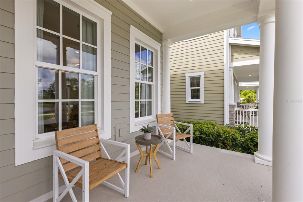 A covered front porch features two wooden chairs, a small side table, and light-colored siding — 2504 CELEBRATION BOULEVARD, CELEBRATION, FL