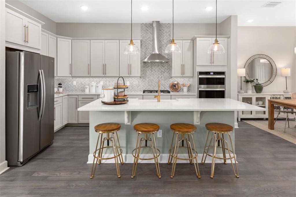 A modern kitchen features light gray cabinets, a white island with four stools, and stainless appliances — 2504 CELEBRATION BOULEVARD, CELEBRATION, FL