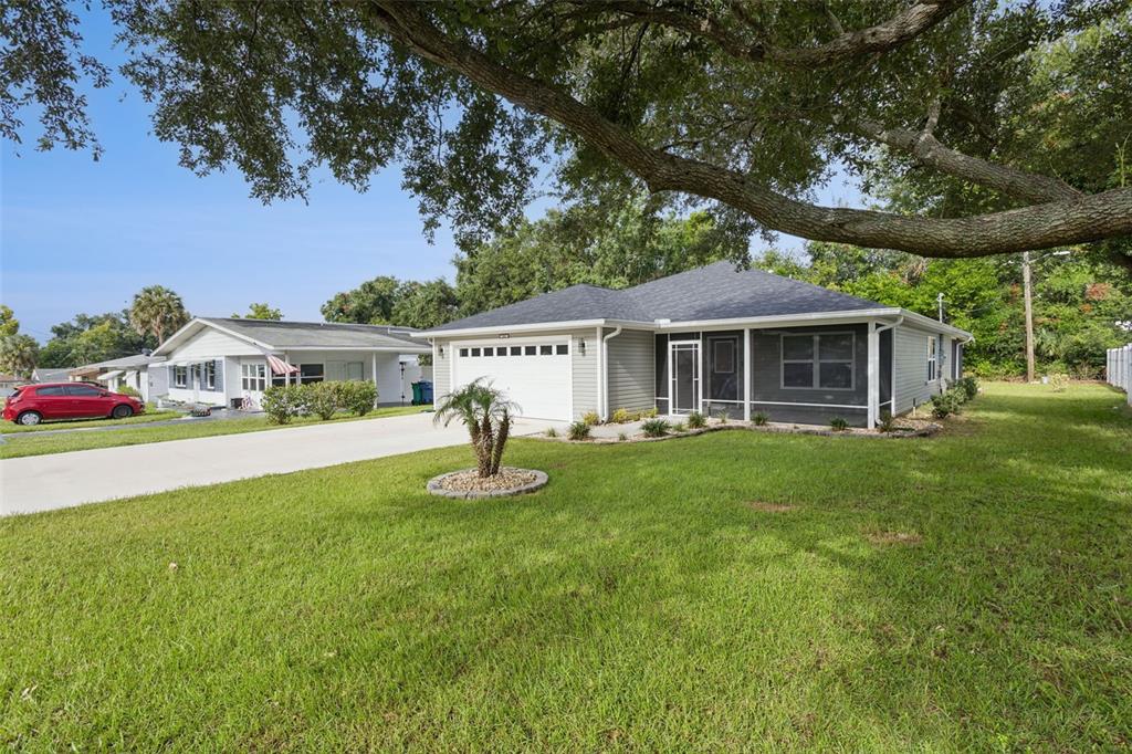 A single-story house with light gray siding, a two-car garage, and a screened-in front porch — 209 JEAN STREET, TAVARES, FL
