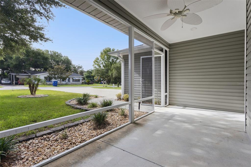 A screened-in concrete patio features a ceiling fan and views of a grassy front yard — 209 JEAN STREET, TAVARES, FL