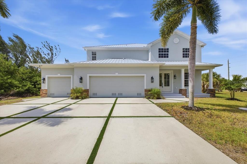 A two-story light-colored house with a three-car garage and a concrete driveway with grass — 15408 MELPORT CIR, PORT CHARLOTTE, FL