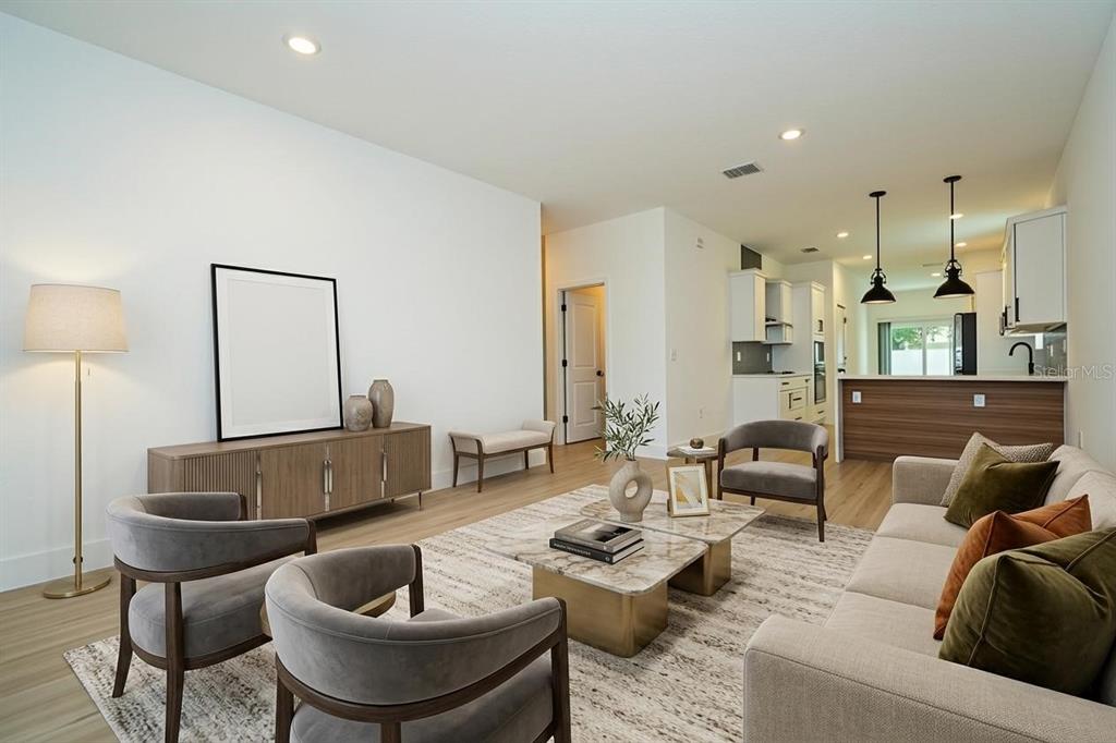 A living room features light wood floors, gray armchairs, a sofa, and an open kitchen — 4419 COLLEGE DRIVE, ORLANDO, FL