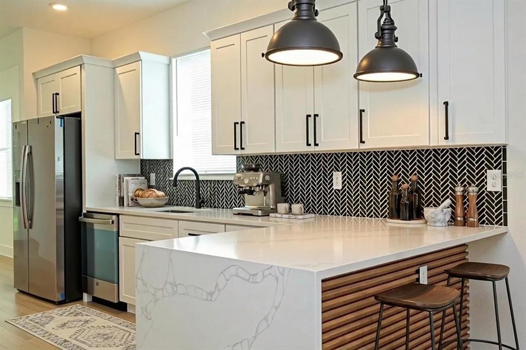 A kitchen features white cabinets, a marble-topped island, and a black herringbone tile backsplash — 4419 COLLEGE DRIVE, ORLANDO, FL