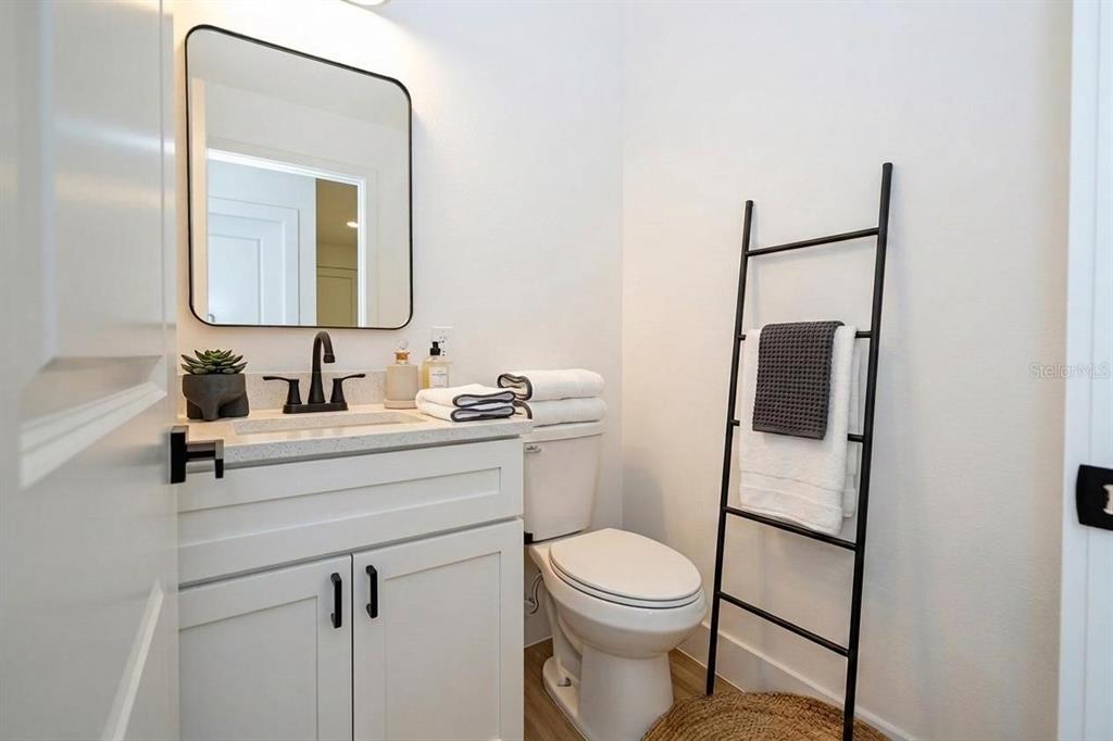 A modern bathroom features a white vanity, a black-framed mirror, and a decorative towel ladder — 4419 COLLEGE DRIVE, ORLANDO, FL