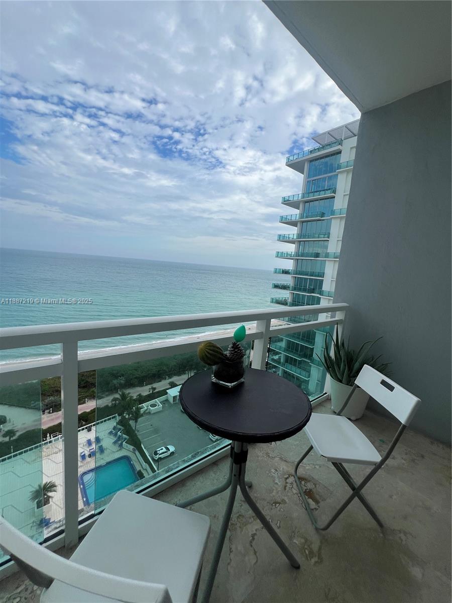 A balcony features a small round table, two chairs, and a view of the ocean — 6917 Collins Ave, Miami Beach FL 33141, MIAMI BEACH, FL