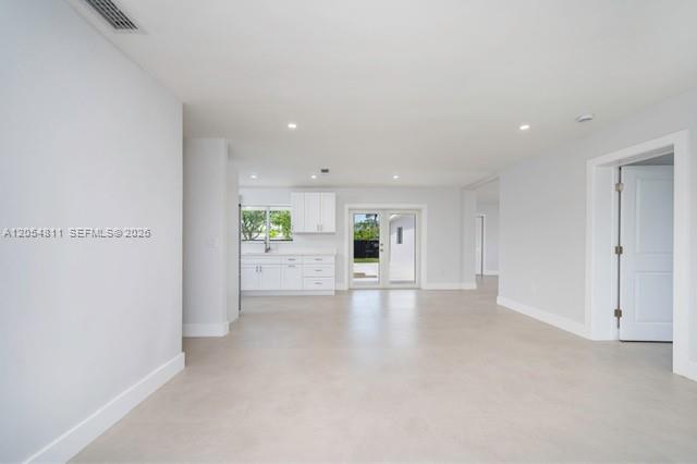An open-concept living area features white kitchen cabinets, light tile flooring, and glass patio doors — 10040 SW 215th St, Cutler Bay FL 33189, CUTLER BAY, FL