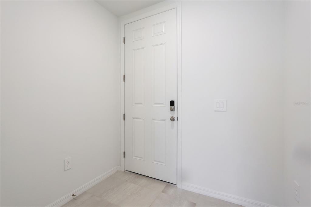 A white six-panel door with a smart lock stands in a room with light flooring — 16332 HAPPY EAGLE DRIVE, CLERMONT, FL
