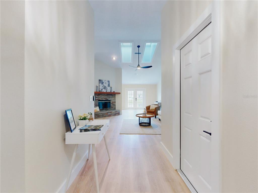 A bright entryway leads into a living room featuring a stone fireplace and skylights — 804 SOFT PINE COURT, NEW SMYRNA BEACH, FL