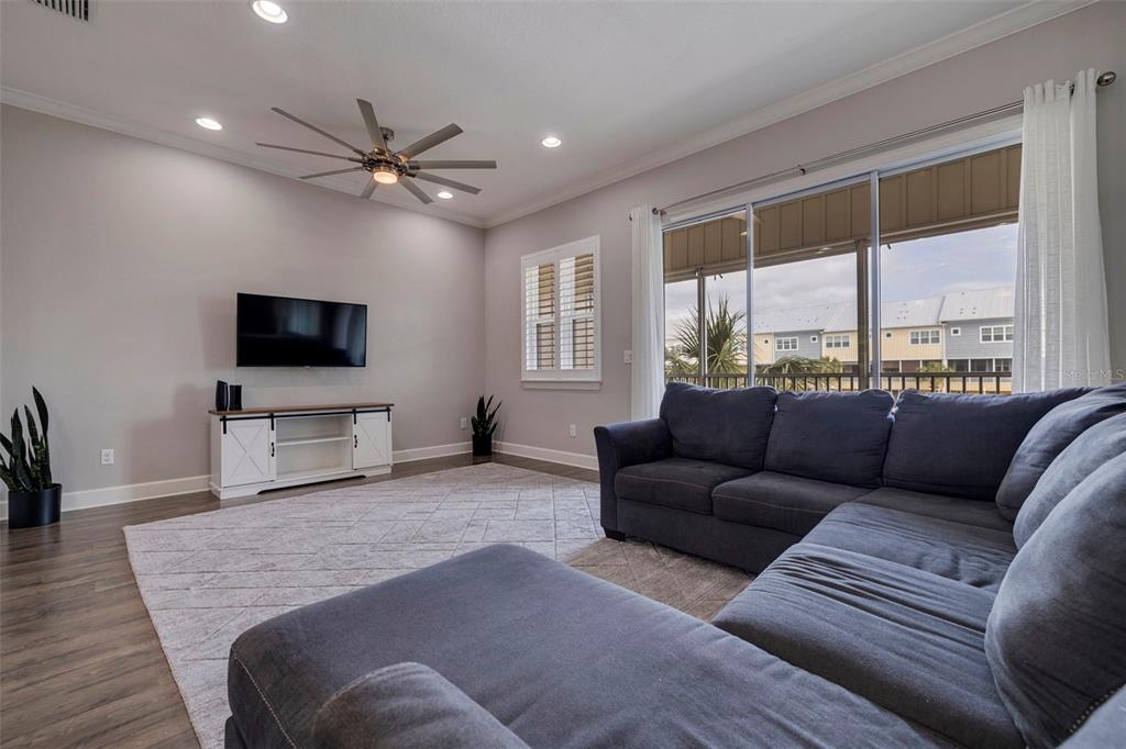 A living room features a grey sectional sofa, a television, and a sliding glass door — 6064 MOORINGS DRIVE S, ST PETERSBURG, FL