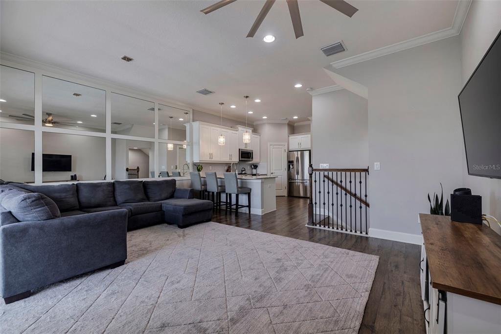 A living room with a gray sectional sofa, area rug, and an open-concept kitchen — 6064 MOORINGS DRIVE S, ST PETERSBURG, FL