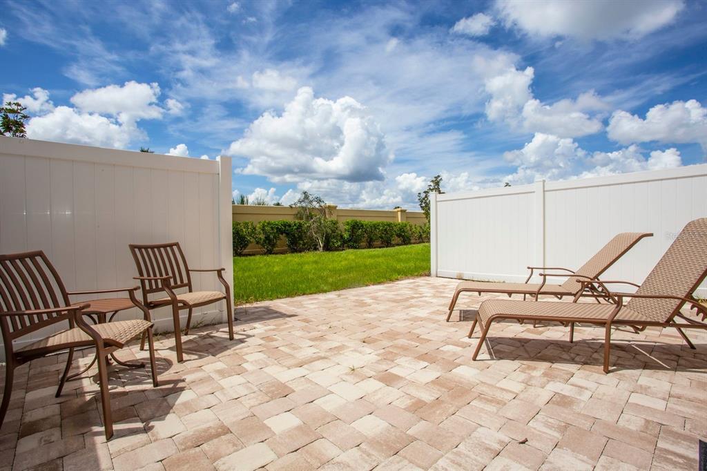 A paved patio features two chairs, a small table, and two lounge chairs outdoors — 5149 ADELAIDE DRIVE, KISSIMMEE, FL