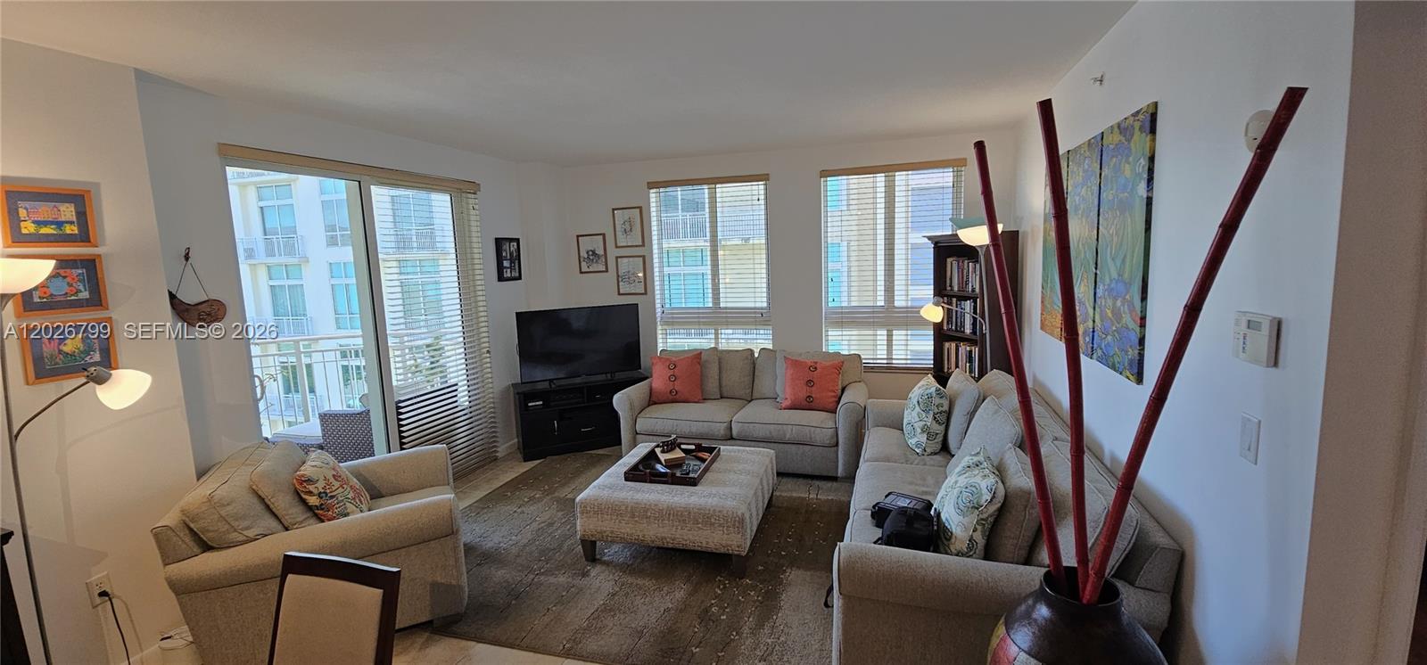 A living room features light-colored sofas, a central ottoman, and large windows with blinds — 7350 SW 89th St # 701S, Miami FL 33156, MIAMI, FL