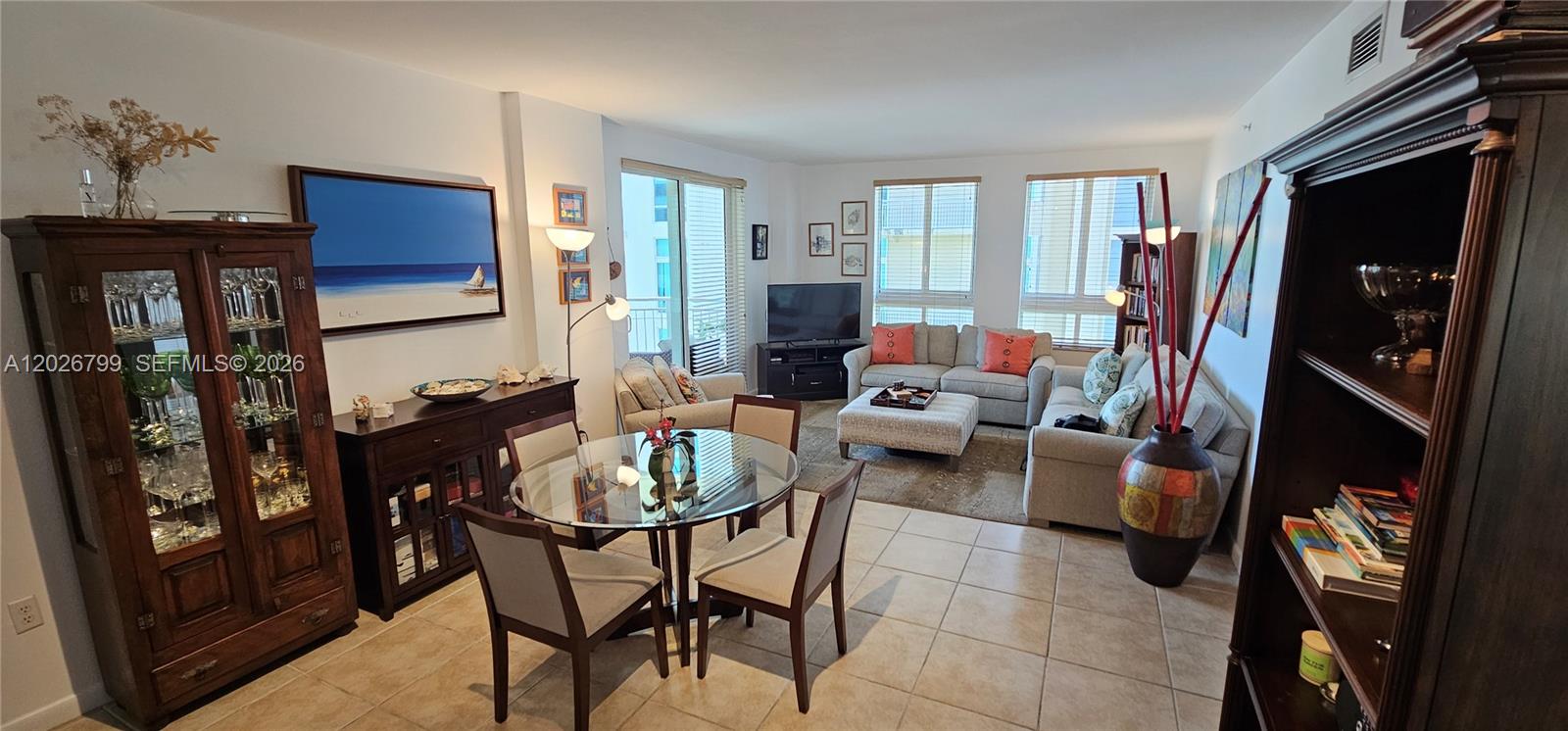 This open-concept living and dining area features tile flooring, a glass-top table, and neutral furniture — 7350 SW 89th St # 701S, Miami FL 33156, MIAMI, FL